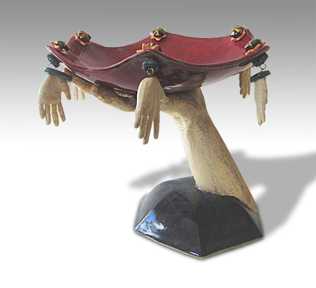 arm and hand holding a hexagon dish aloft, which is decorated with hands as jewelry